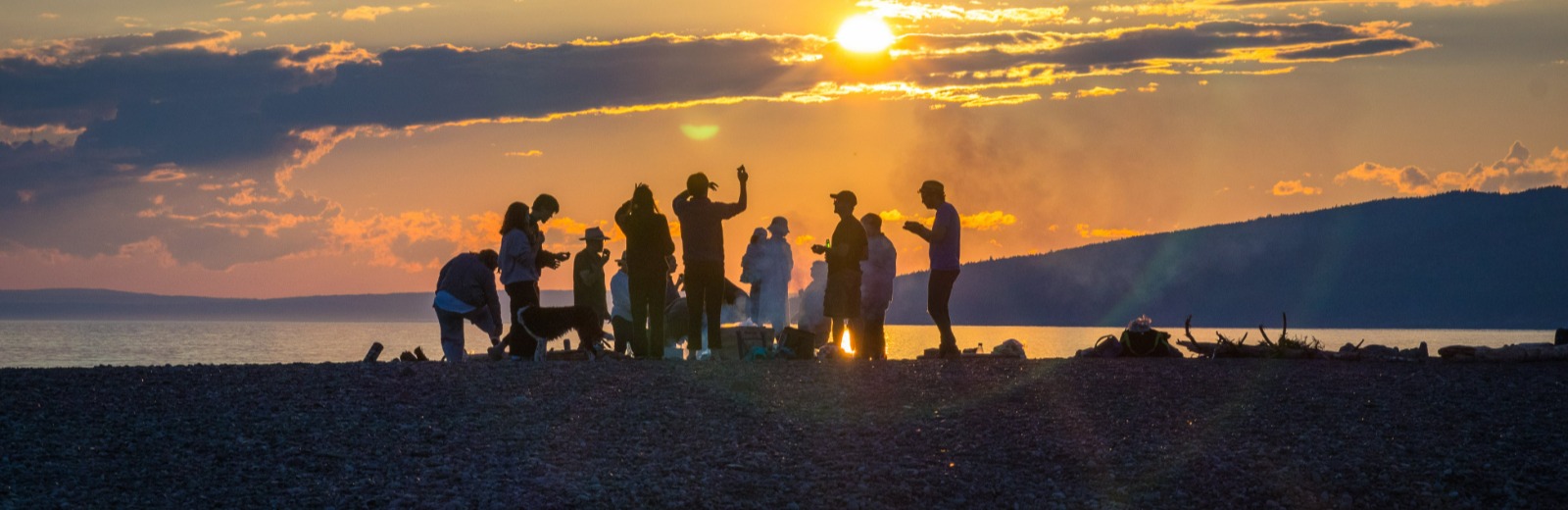 family around a bonfire on the beach at sunset